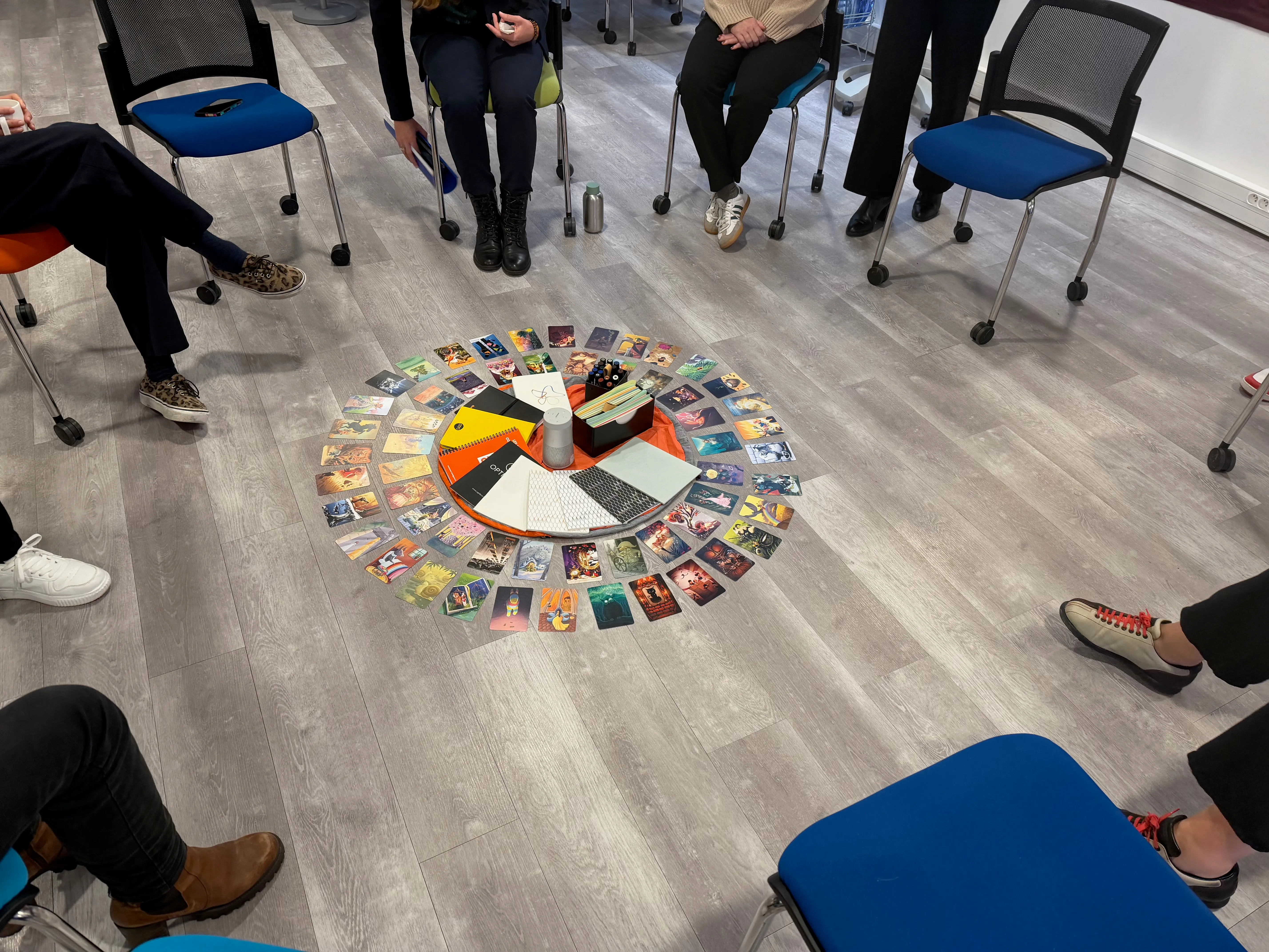Vue de dessus d'un cercle de chaises autour d'un tapis de cartes de photolangage et de feutres posés au sol