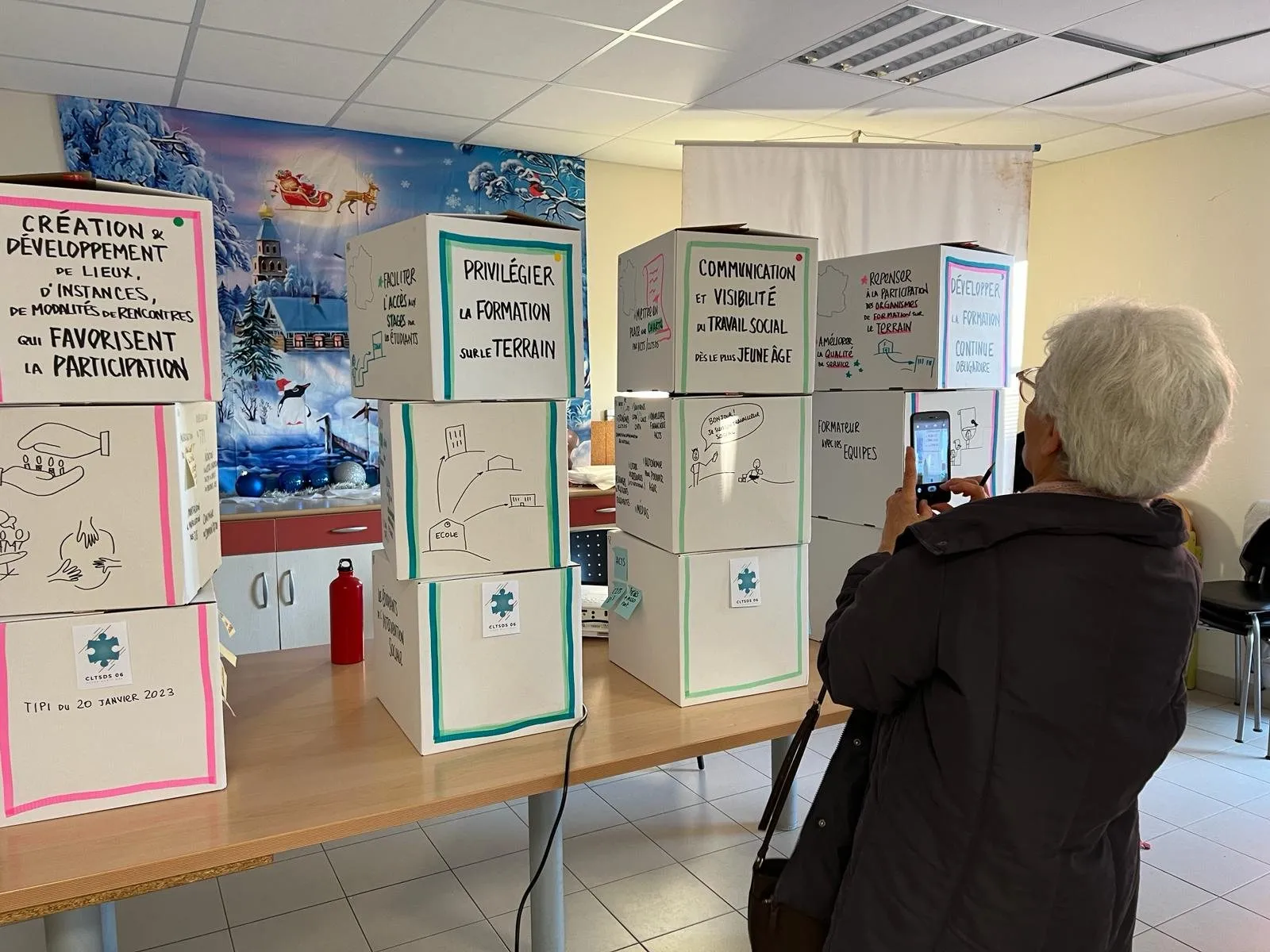 Trois totems de restitution en carton dressés dans une salle, chacun couvert de dessins et de post-its